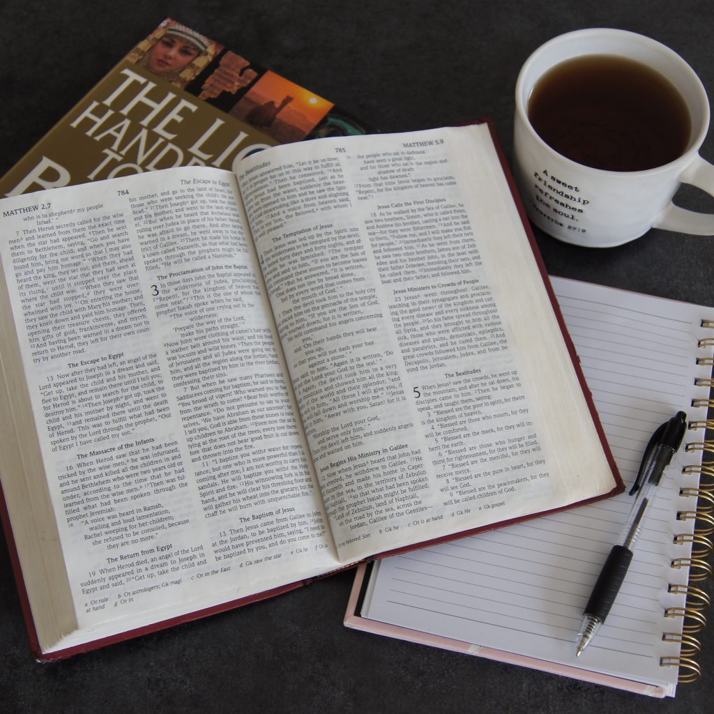 Photo of a Bible, journal, pen, and coffee cup.