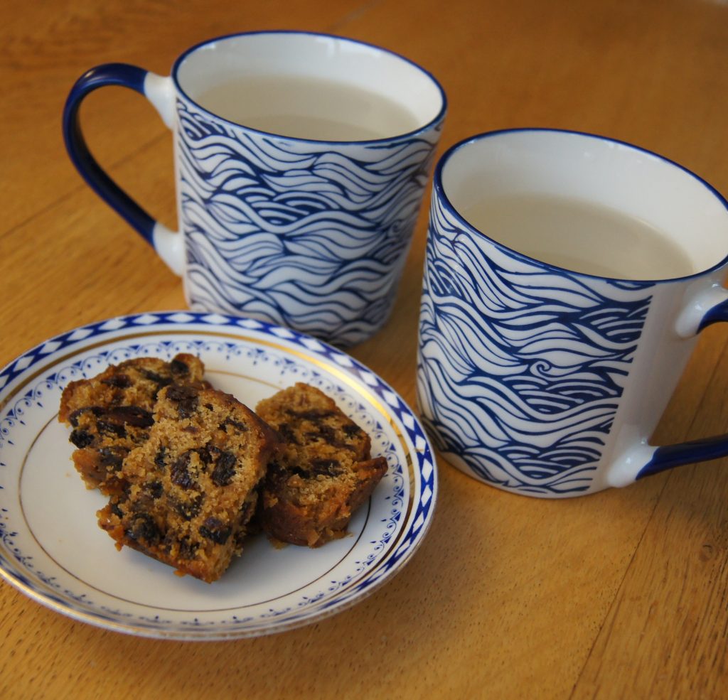 Photo of two coffee cups and a saucer with three slices of fruit cake